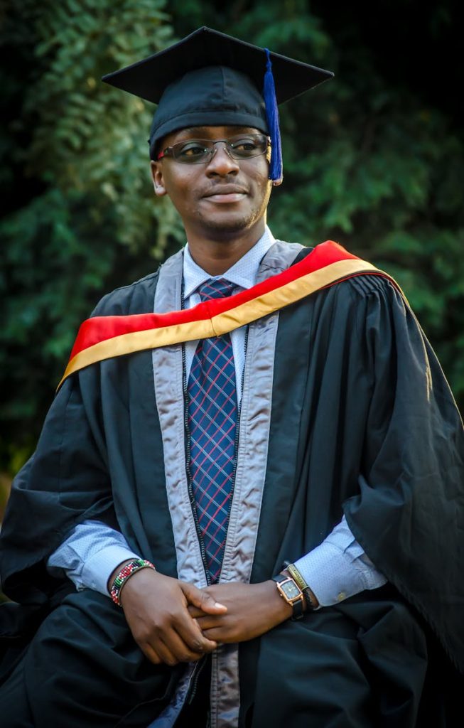 A joyful graduate wearing academic regalia poses outdoors, celebrating success.