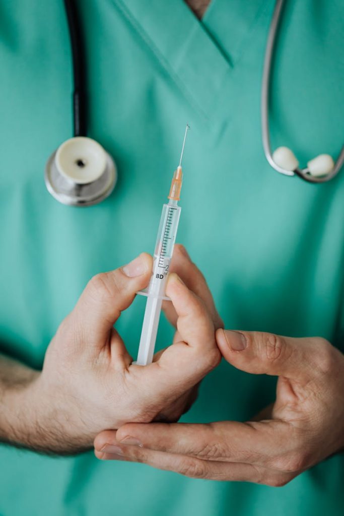 Doctor holding a syringe, ready for injection, with stethoscope.