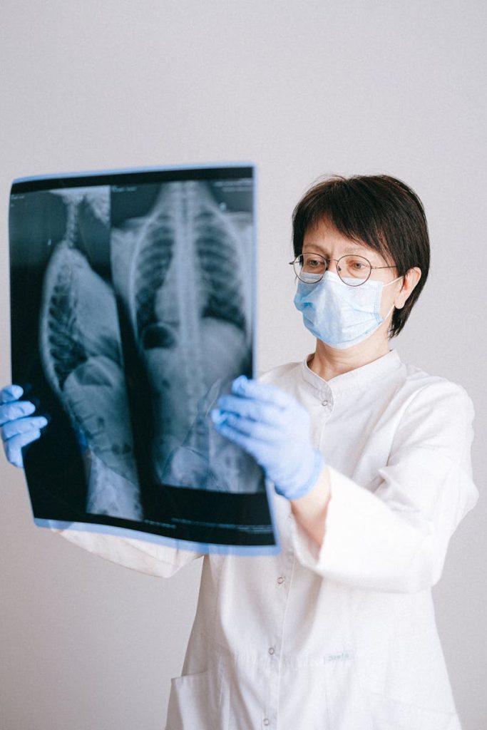 Medical professional in PPE examining chest X-ray results for diagnosis.